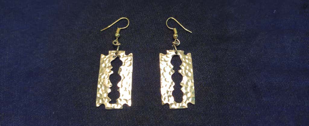 Pair of silver razorblade-shaped earrings on a dark blue background